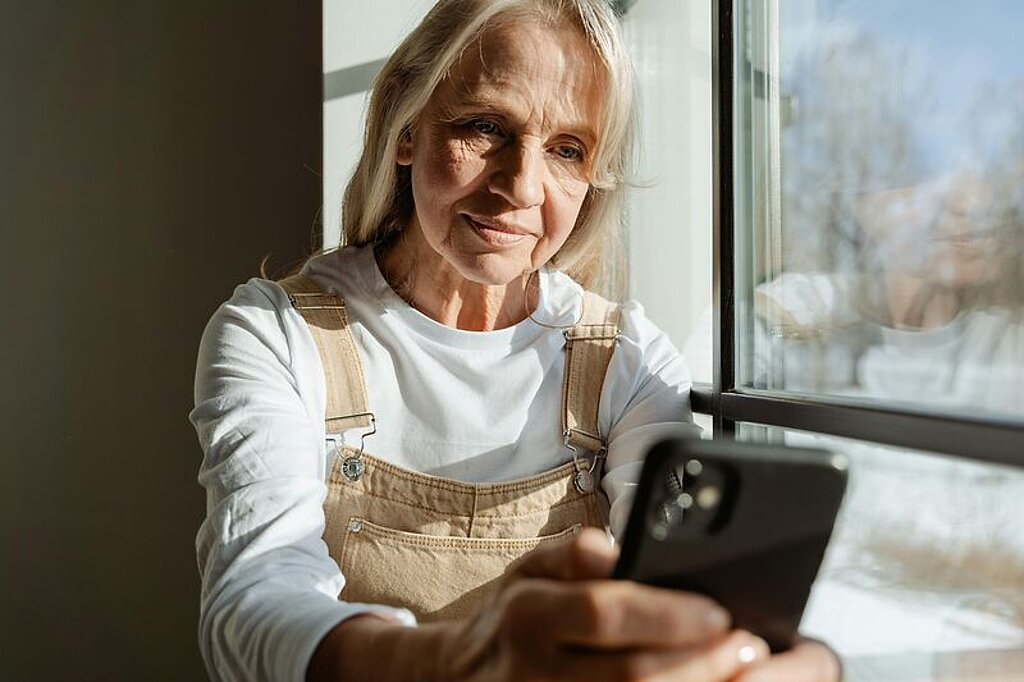 Frau mit Handy Frau mittleren alters schaut in ihr Mobiltelefon.