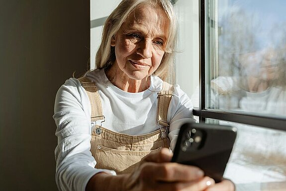 Frau mit Handy Frau mittleren alters schaut in ihr Mobiltelefon.